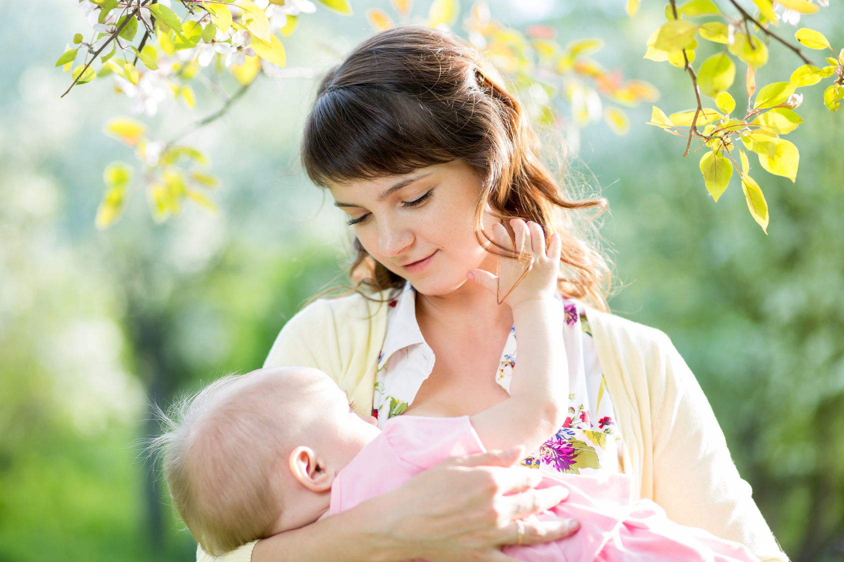 young mother breast feeding her baby girl outdoors