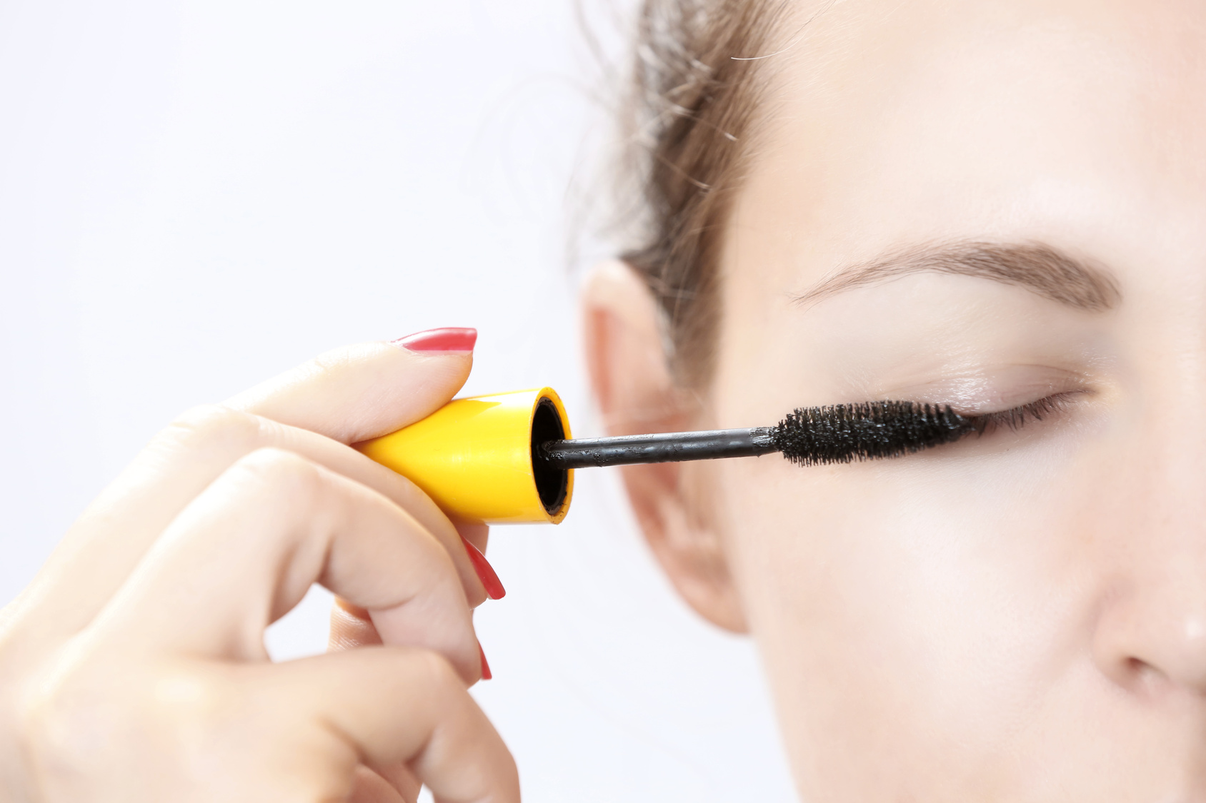 Woman applying mascara on eyelashes