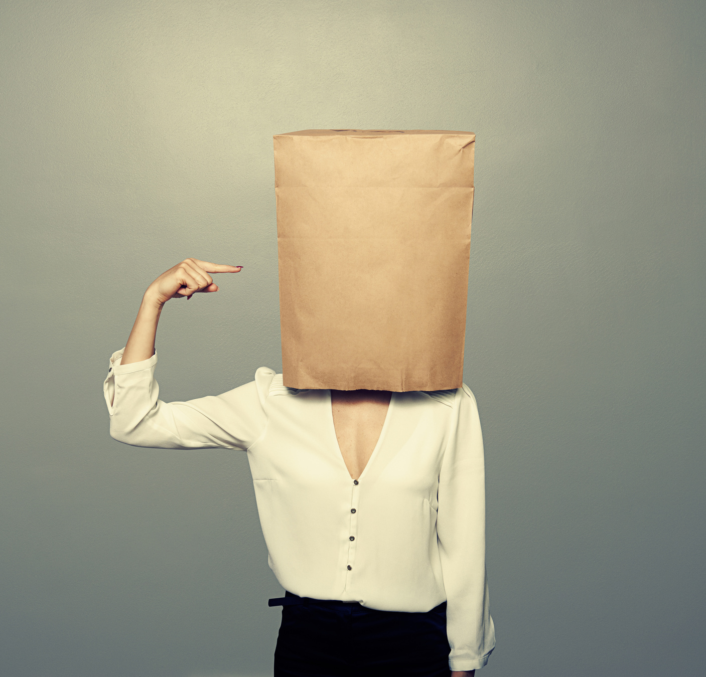 woman pointing at paper bag on the head