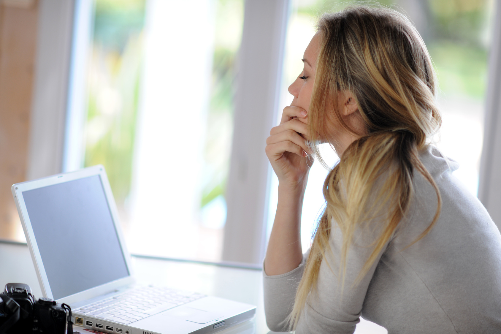 Woman sitting in front of laptop with thoughtful look