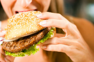 Frau im Restaurant isst Hamburger
