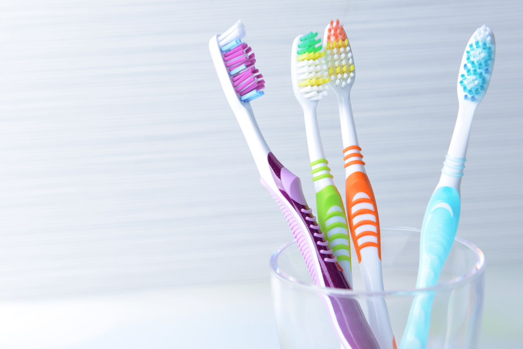 Toothbrushes in glass on table on light background