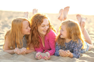 mother and her two daughters on the beach in summer