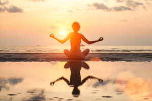Young woman is practicing yoga at Sea beach.