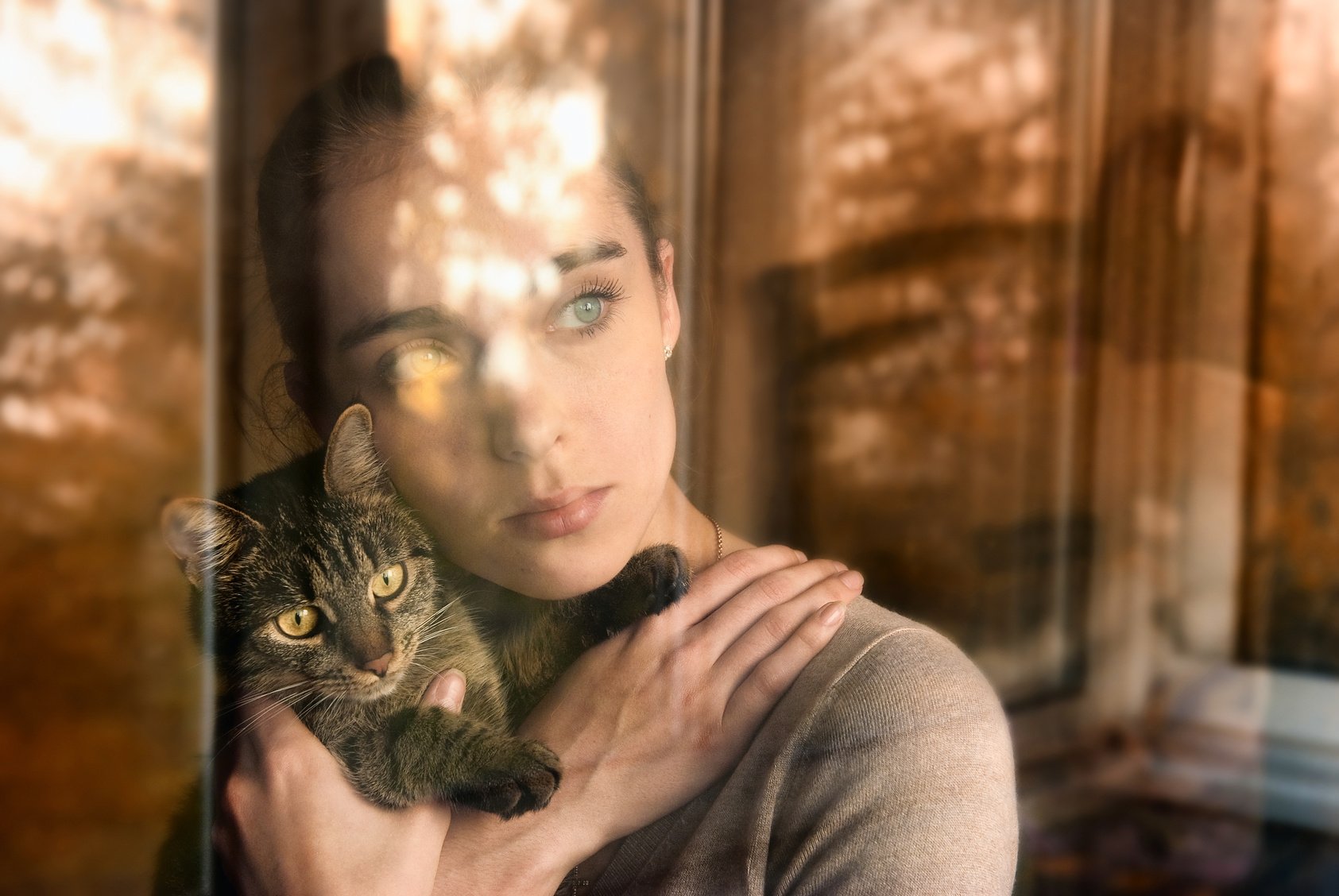 Beautiful woman with a cat and sits by the window