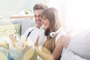 Young trendy couple having fun playing with smartphone