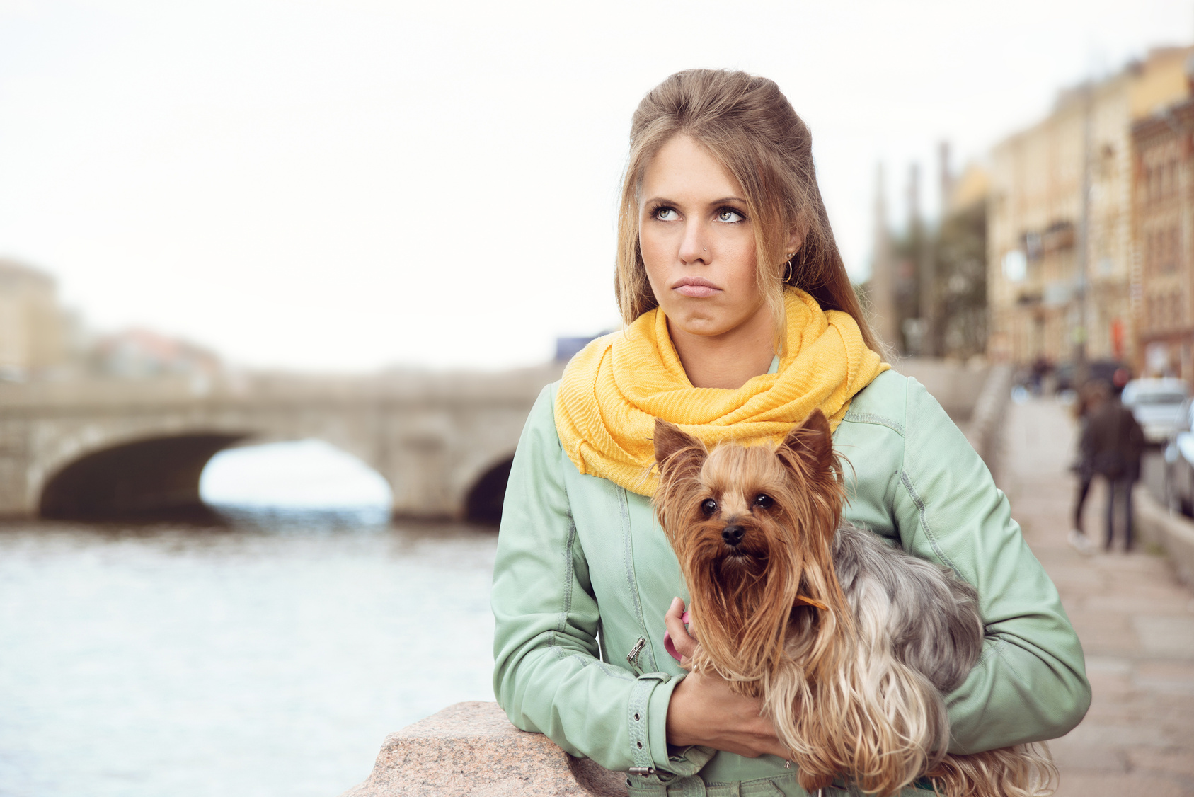 Sad girl with little dog on the bank of the river