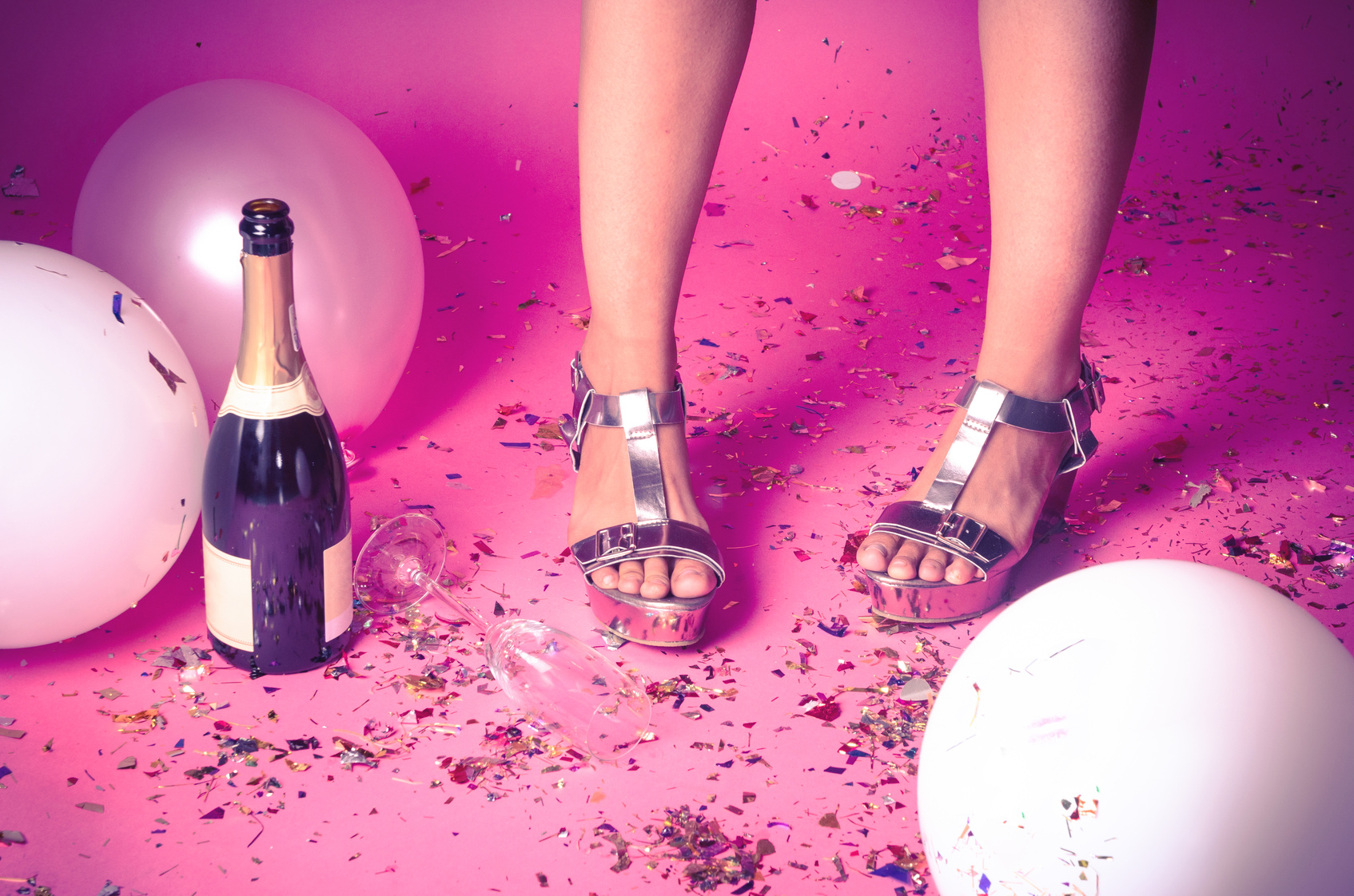 Woman’s feet with confetti on the floor and champagne