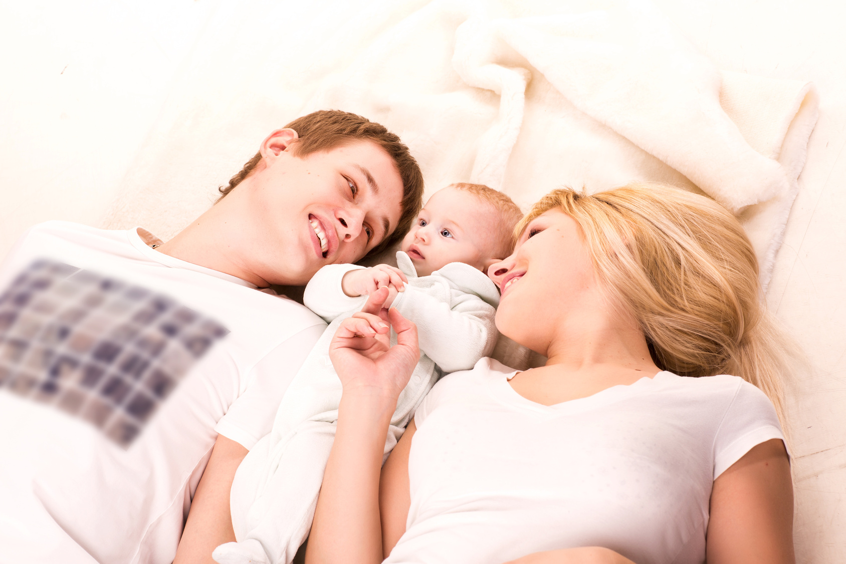 Young happy family: mother, father and baby lying