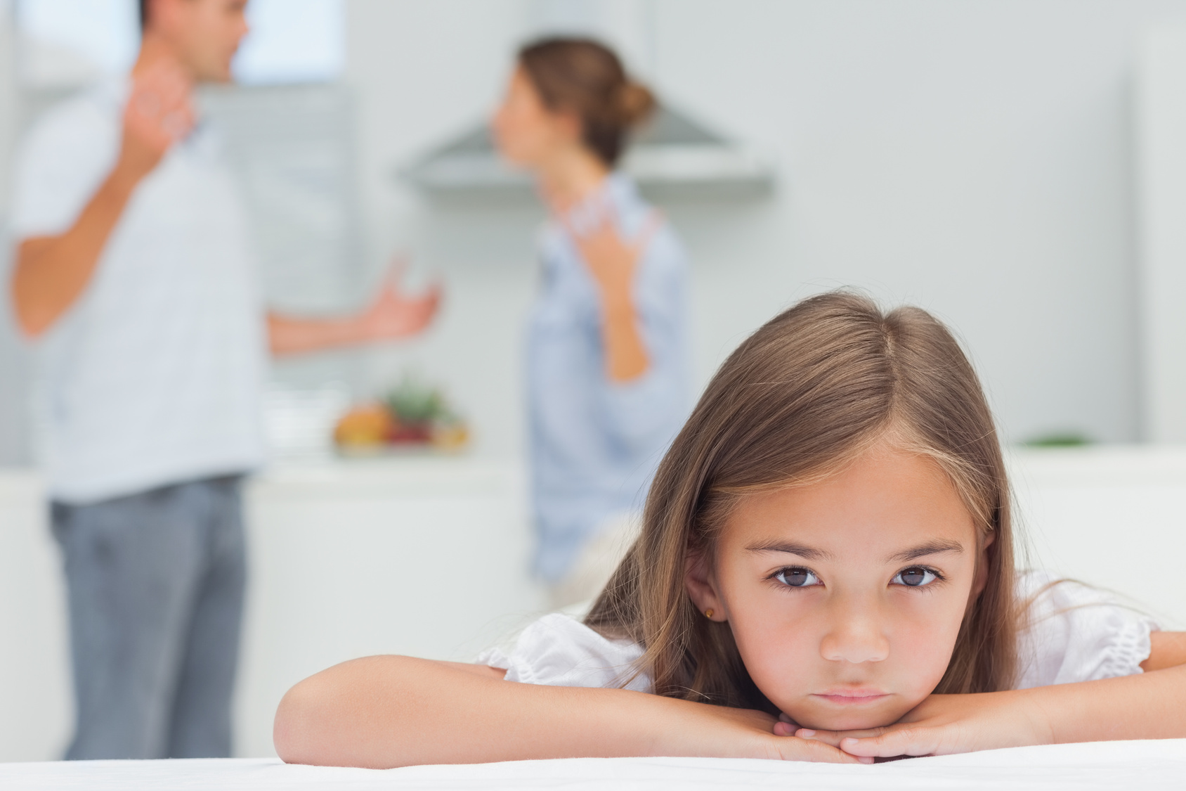 Upset girl listening to parents quarreling in the kitchen