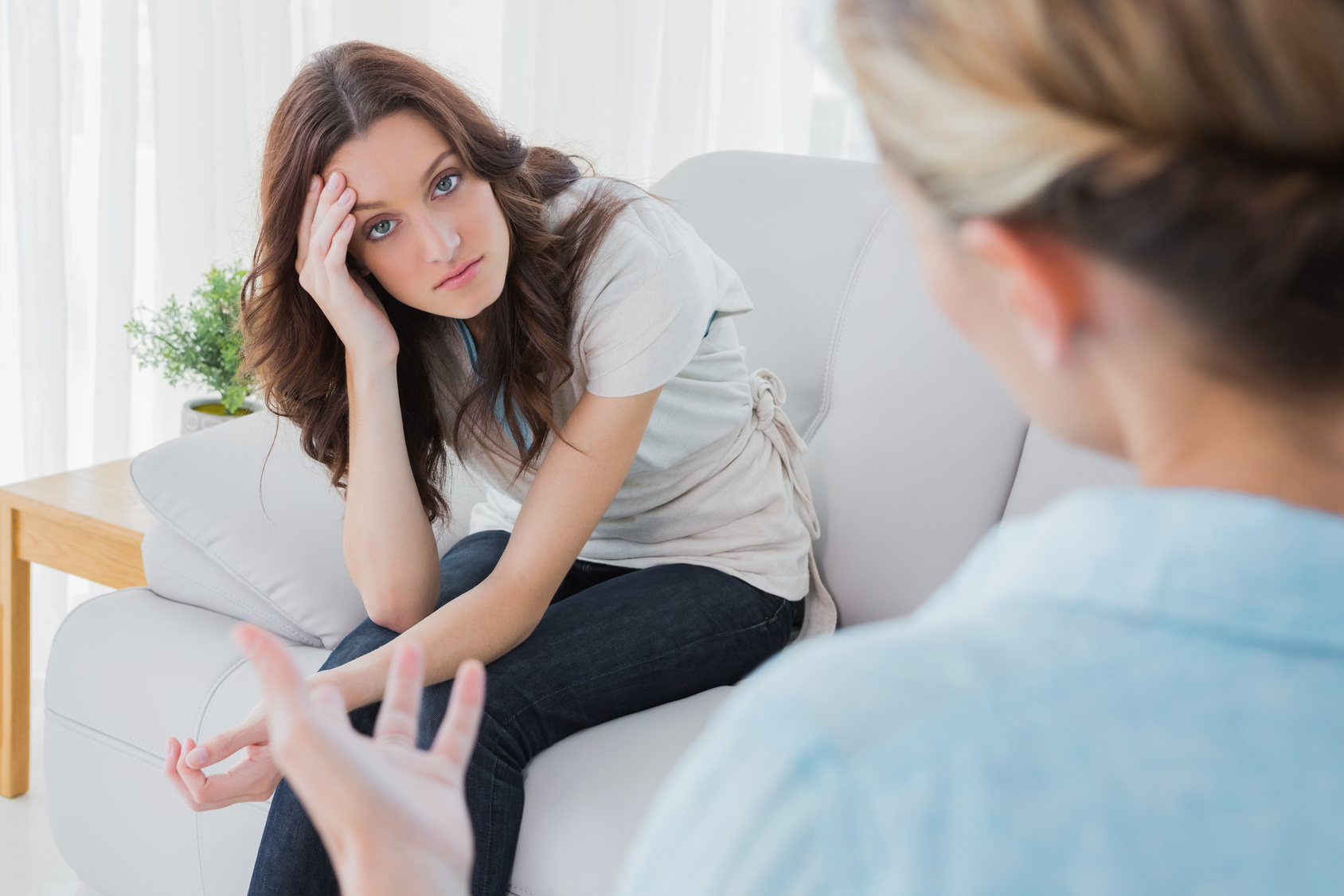 Worried woman sitting and looking at camera during therapy session in office