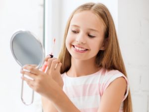 teenage girl with lip gloss and mirror