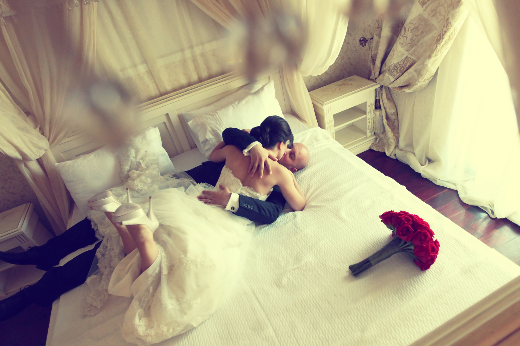 bride and groom lying in a stylish white bed