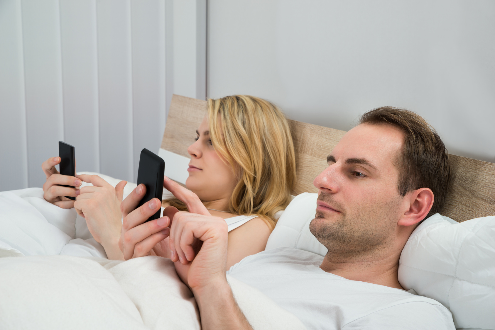 Couple With Mobile Phones In Bed