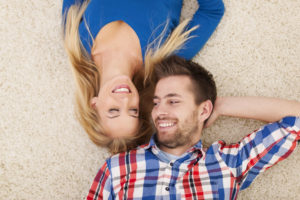 Cute young couple lying on carpet and look at each other