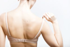 Woman holding a skin colored bra strap