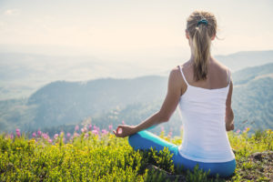 Young woman meditate on the top of mountain