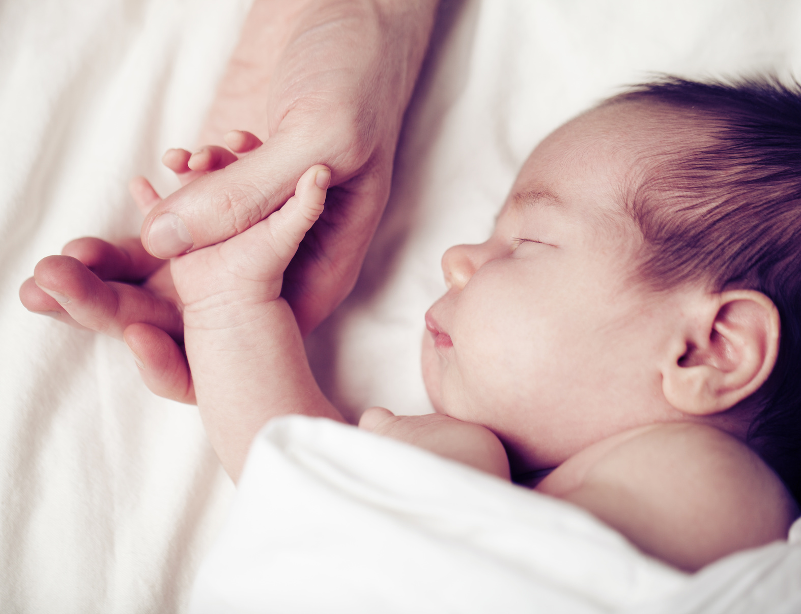 Newborn baby and his father’s hand – care and safety concept