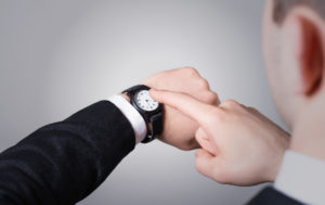 Man’s hand in the suit pointing on his watch