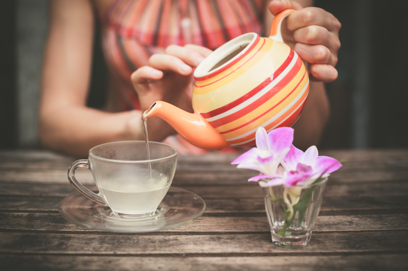 Young woman pouring tea at table