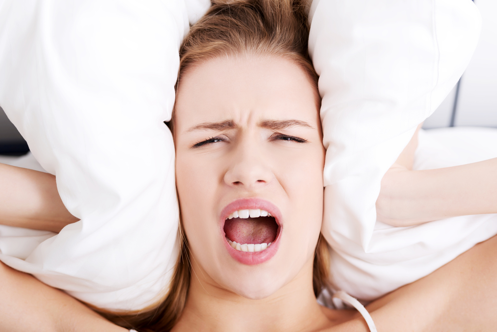 Beautiful business woman lying in bed and covering her ears with