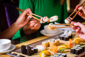 Young people eating sushi in Asian restaurant