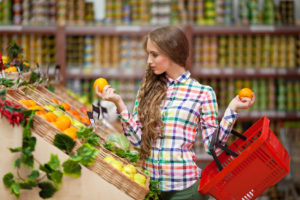 Молодая девушка выбирает фрукты в магазине