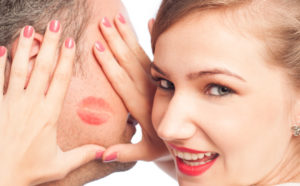 Woman framing lipstick kiss on a man face.