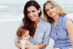 two beautiful girls with a baby on the beach