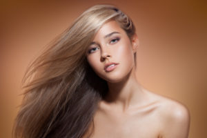 Beautiful Blond Girl. Healthy Long Hair. Brown Background