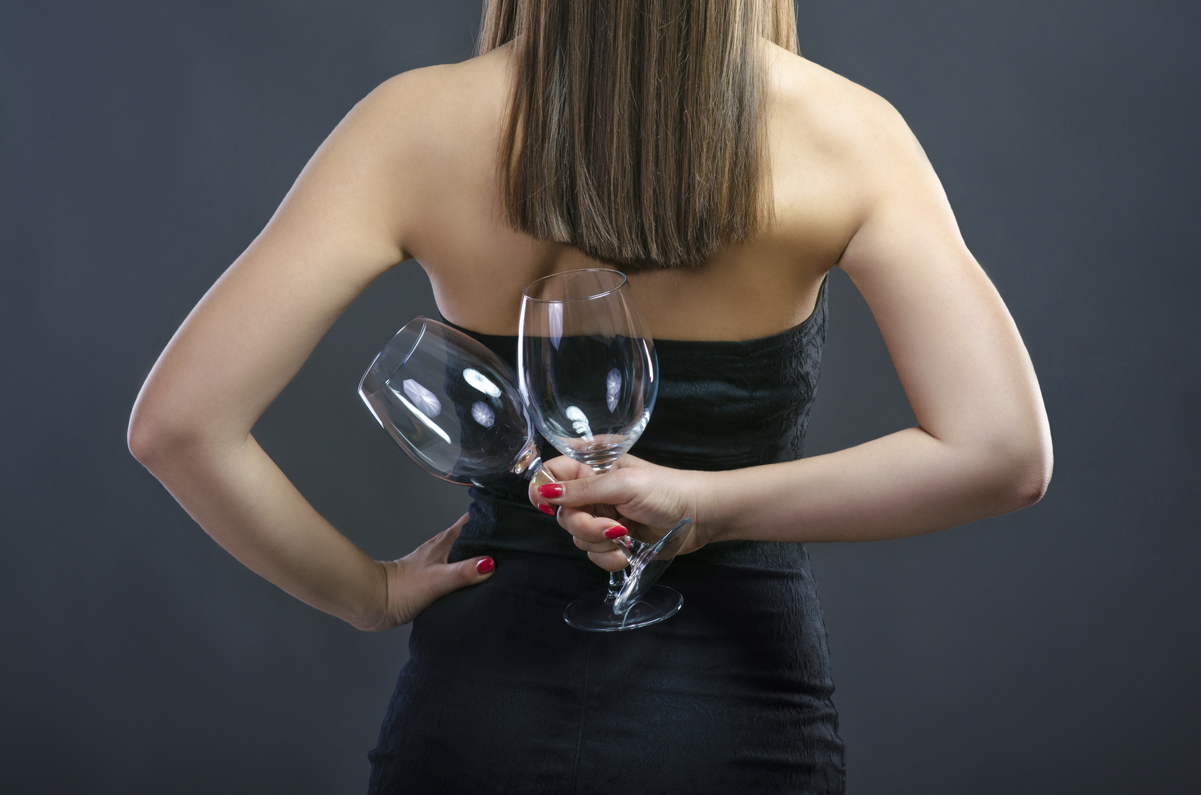 Young woman holding glasses behind her back