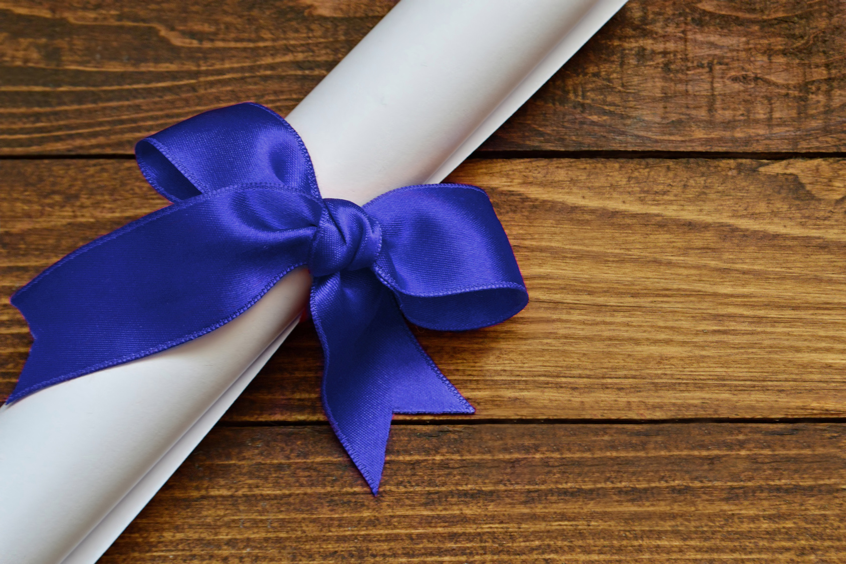 Graduation diploma scroll on wooden background