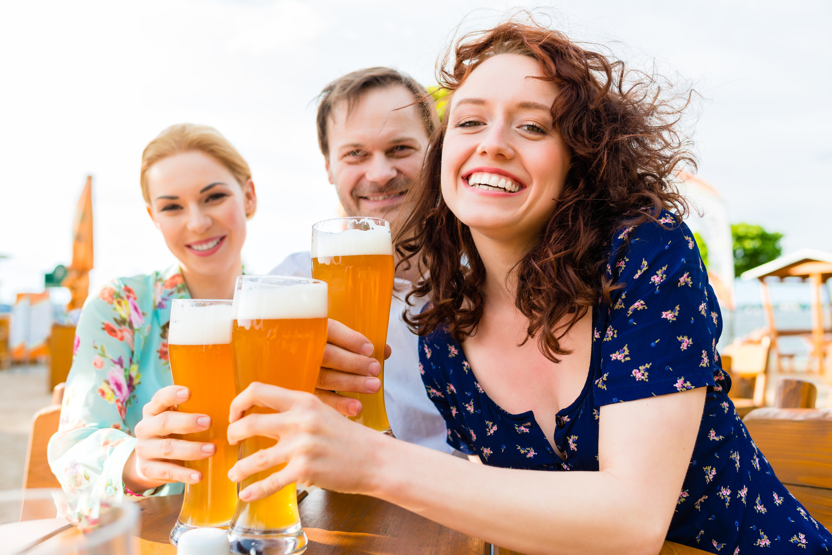 Friends toasting with beer in garden restaurant