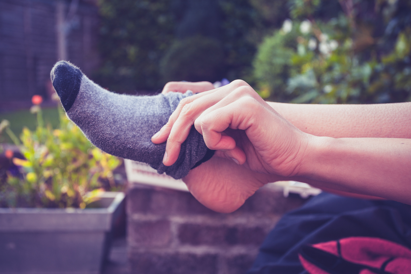 Young woman putting on socks outside