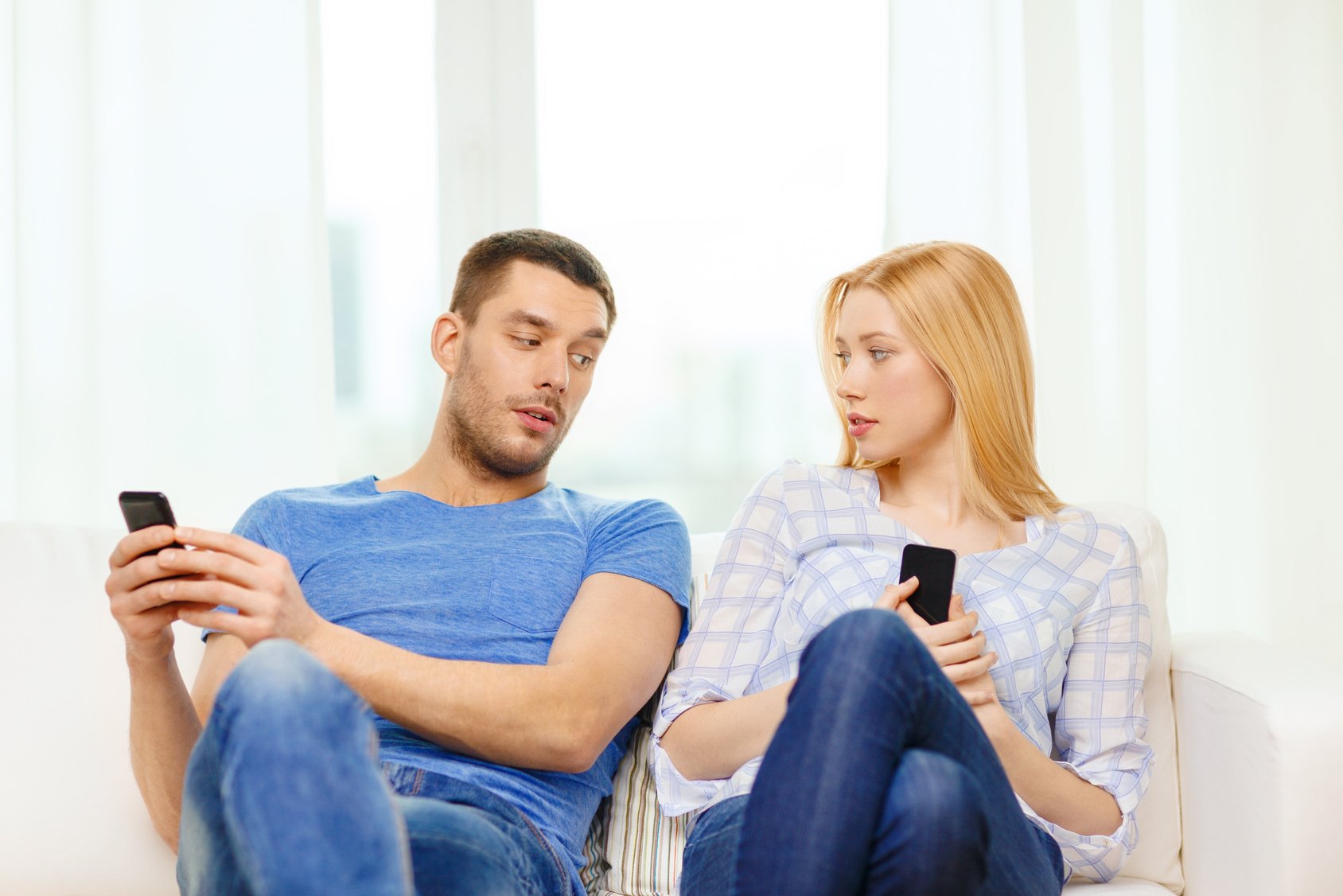 concentrated couple with smartphones at home