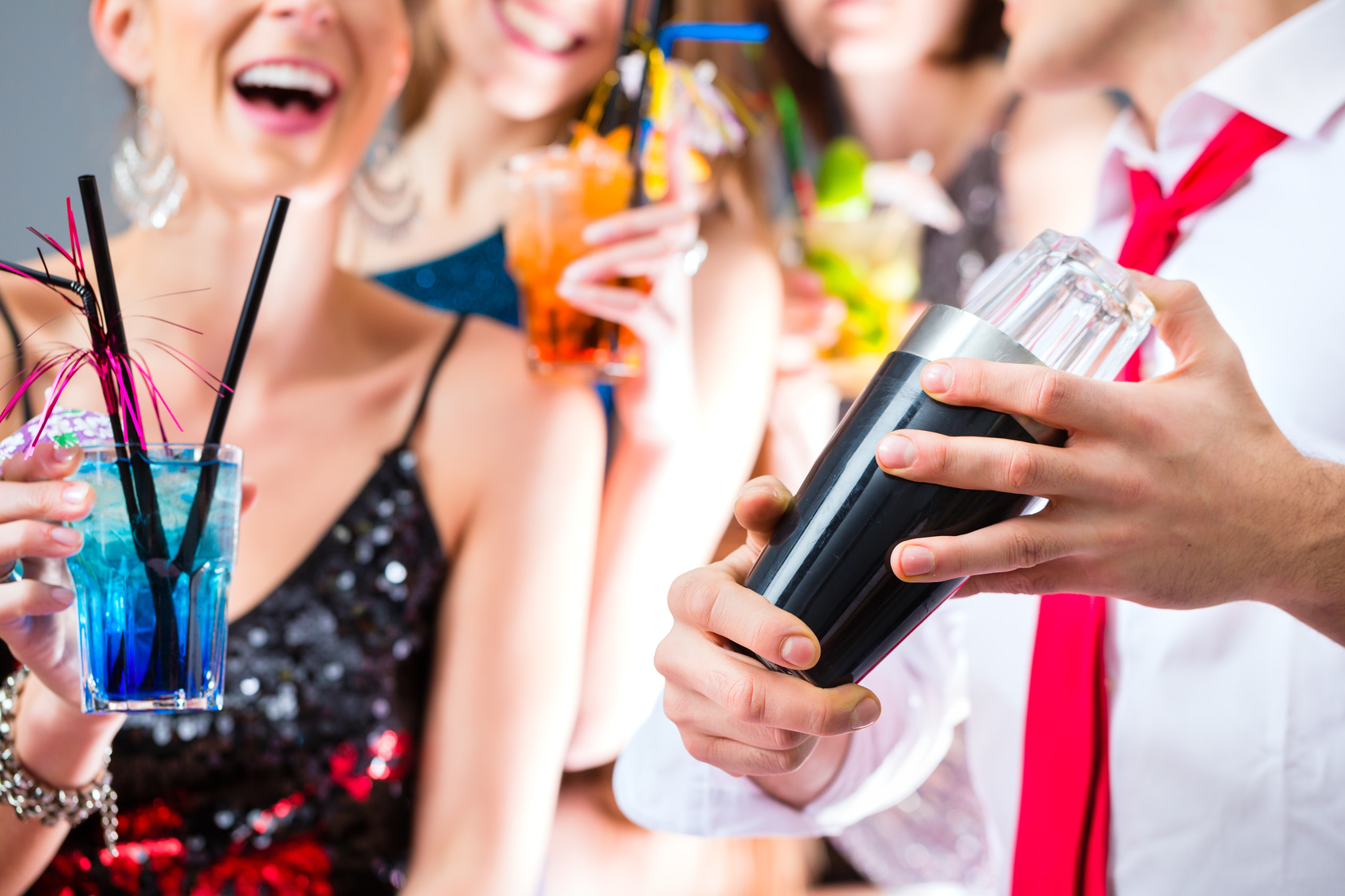 Girls celebrating with barkeeper in cocktail bar