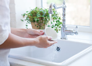 Woman washing dish in sink