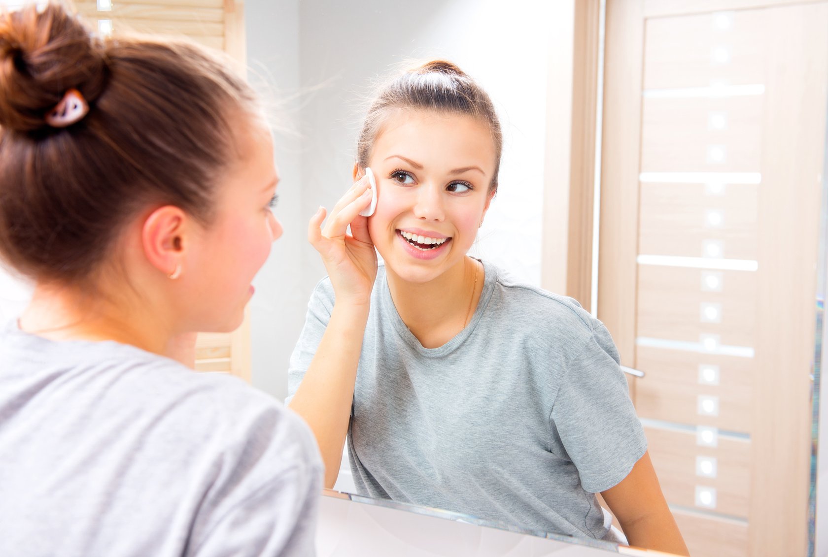 Beauty girl cleaning her face with cotton pad at home