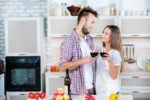 Romance in the kitchen. Beautiful loving couple holding glasses
