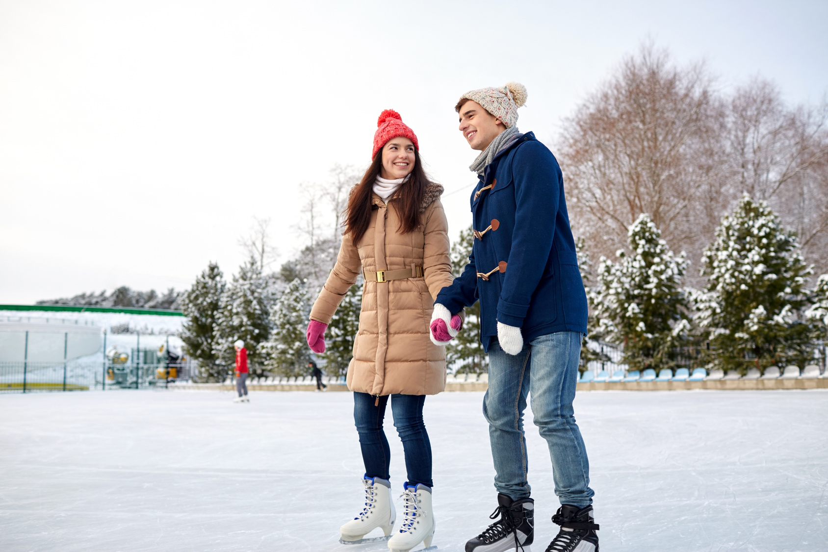 happy couple ice skating on rink outdoors