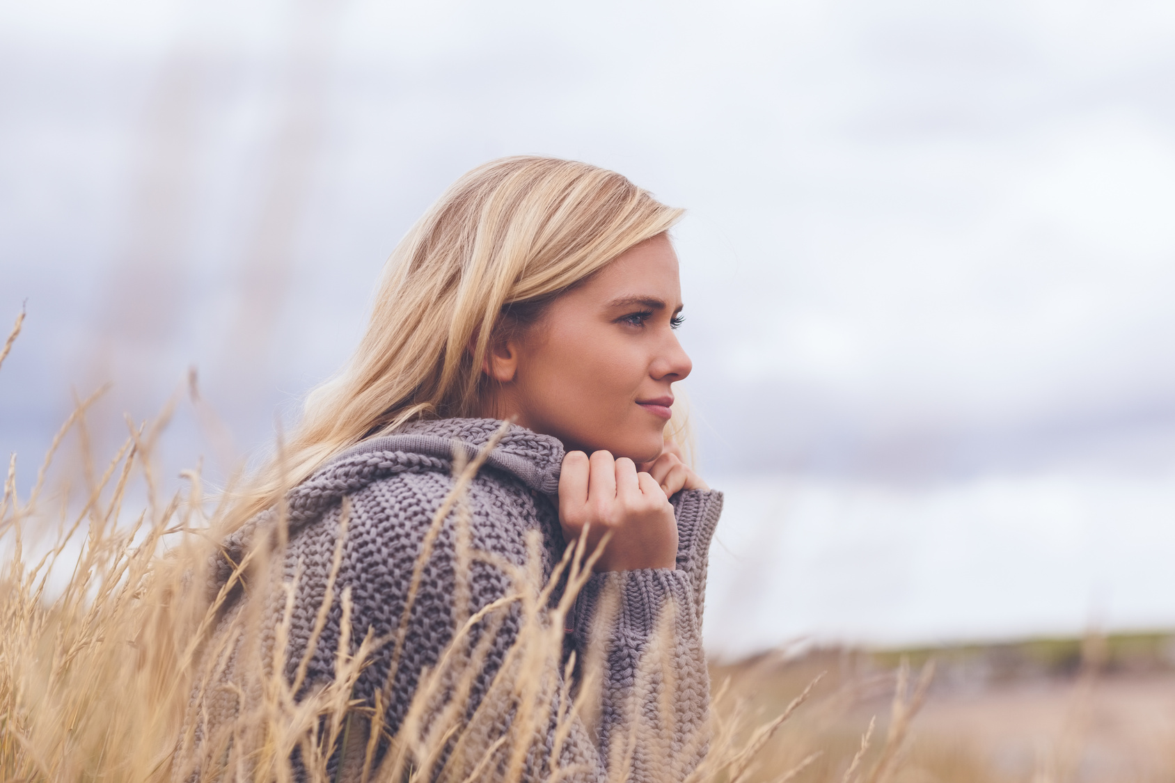 Close up side view of a cute thoughtful young woman lying on grass at beach