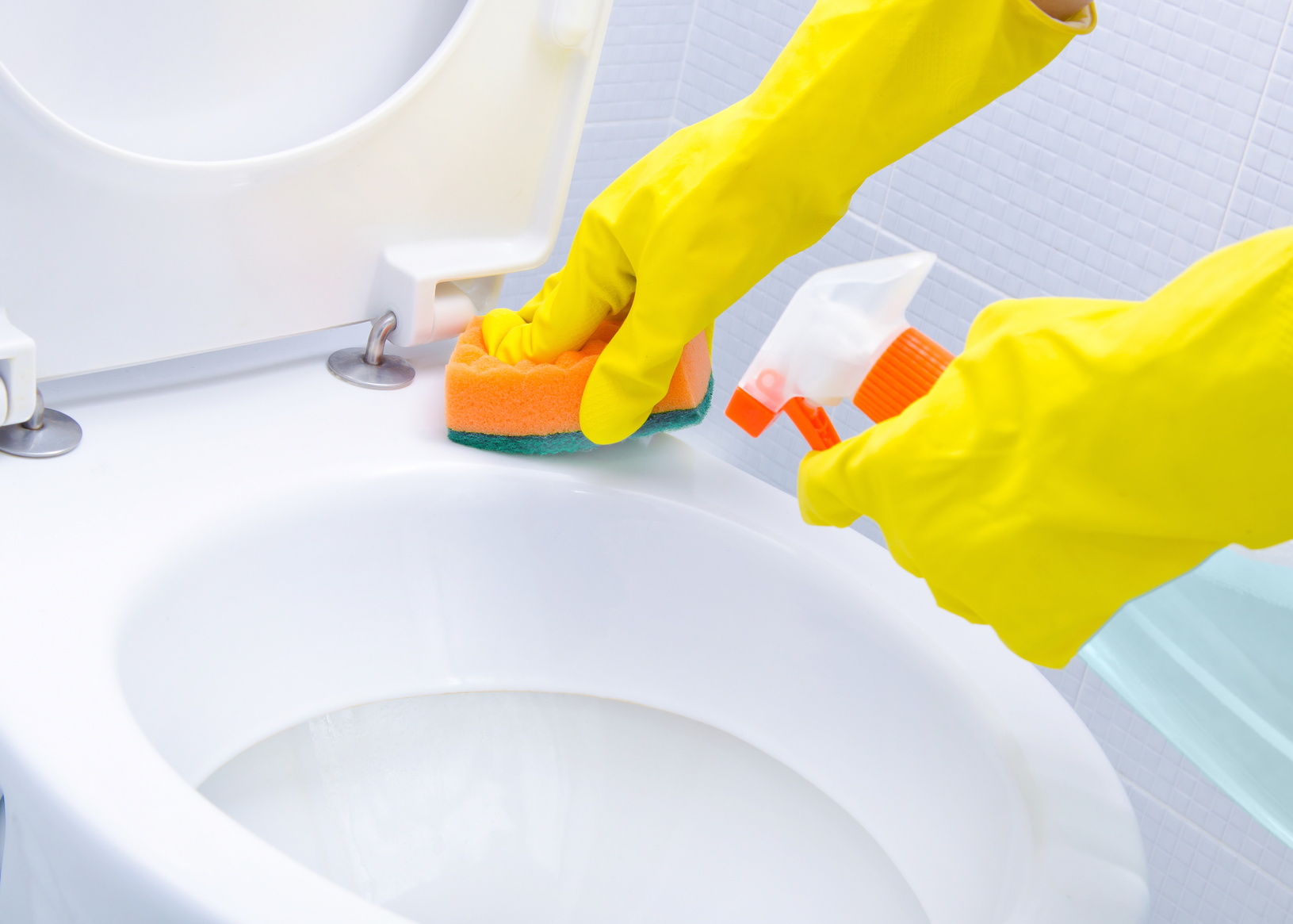 Hands on yellow gloves cleaning a WC