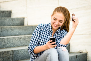 Teenager eating chcolate looking in phone