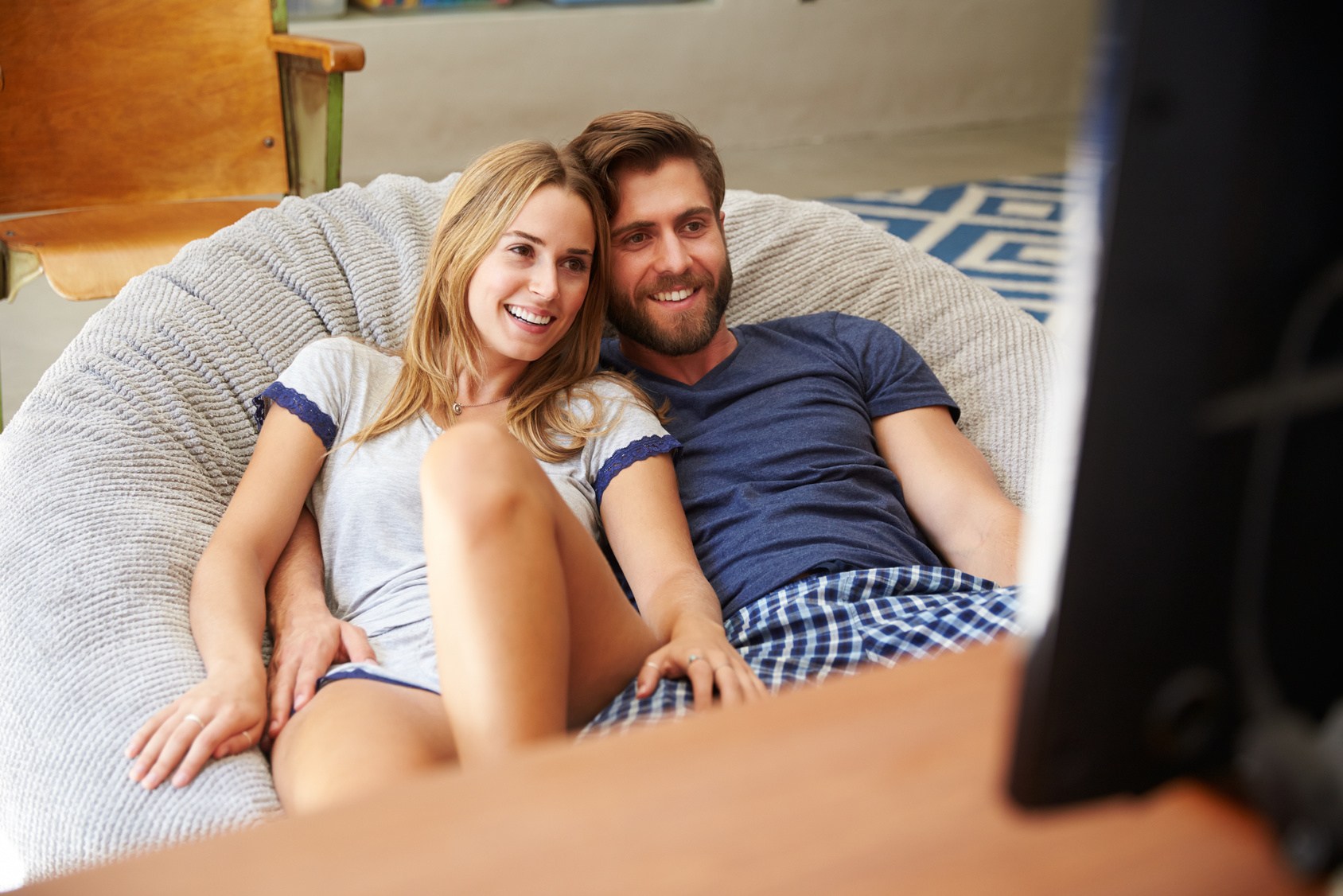 Young Couple In Pajamas Watching Television Together