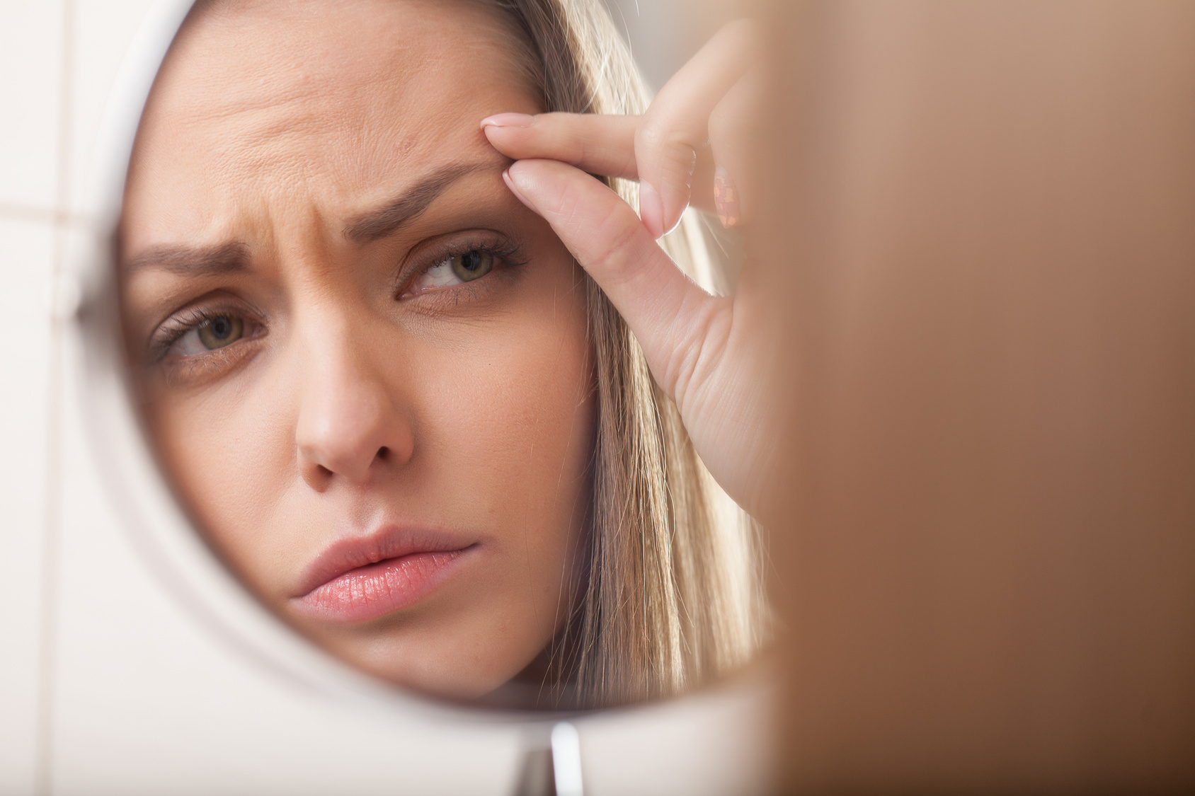 closeup of young woman looking into mirror.