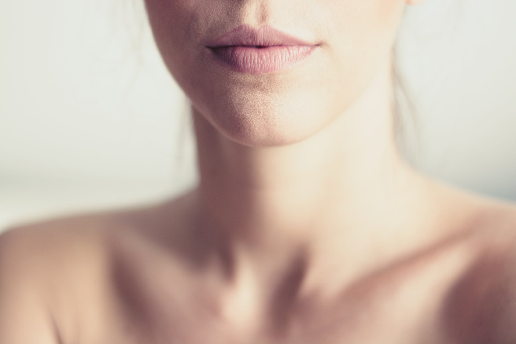 Closeup of young woman’s pink lips and neck