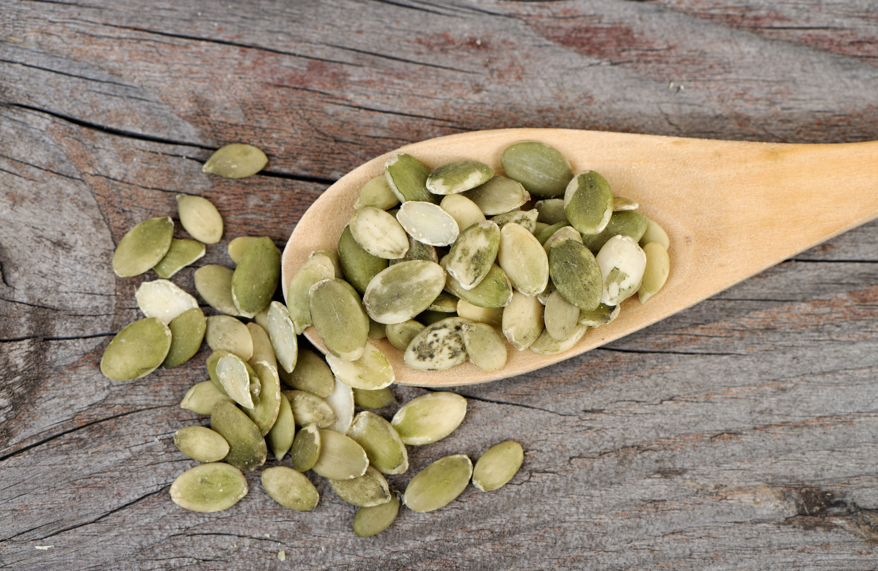 Pumpkin seeds in a wooden spoon. Top view.