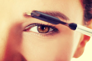 Beautiful woman brushing her eyebrow.