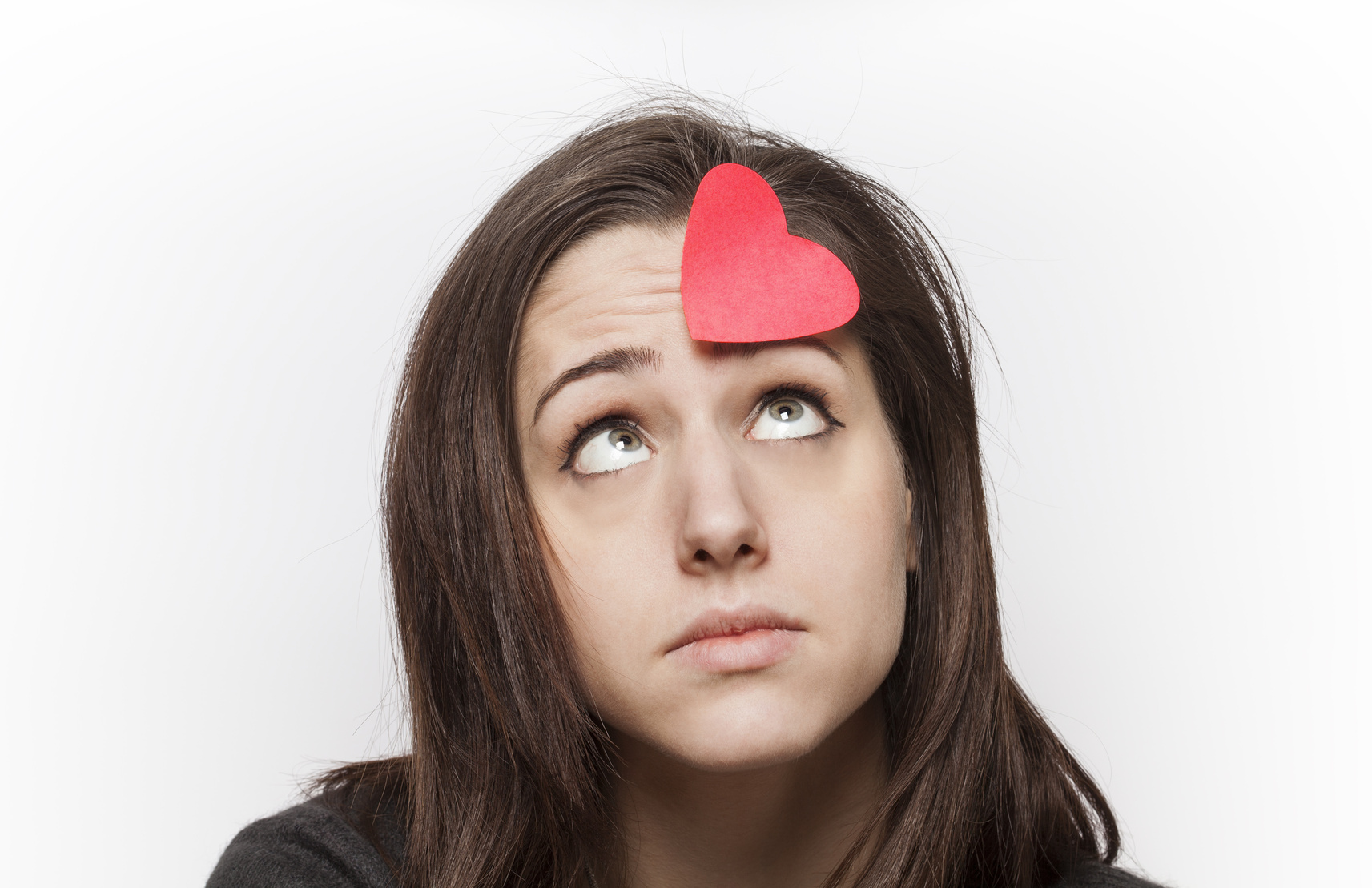 Sad girl looking at a paper heart on her forehead
