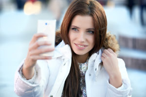 pretty young woman taking a picture on town